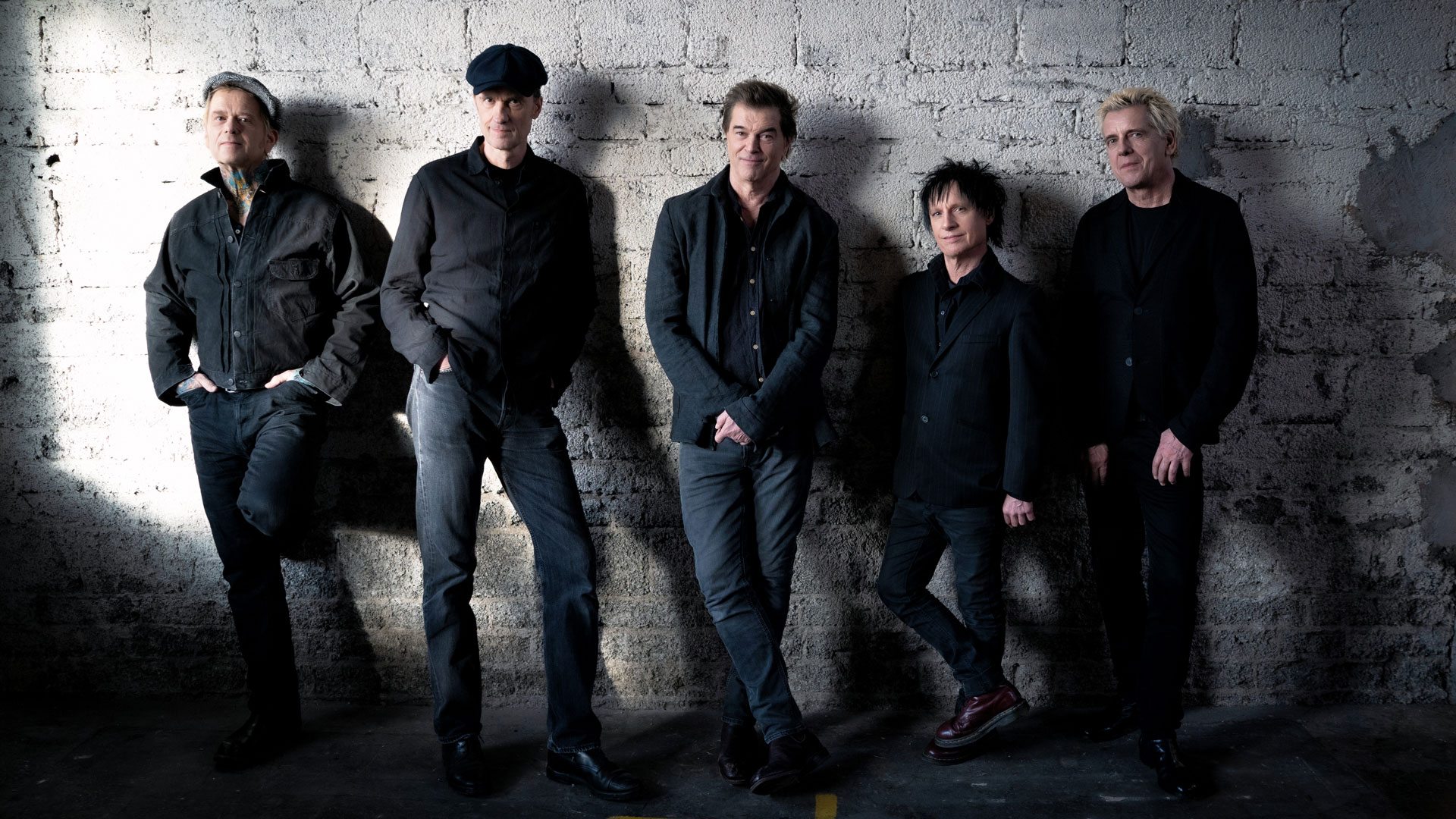 Die Toten Hosen lehnen an einer weißen Wand.